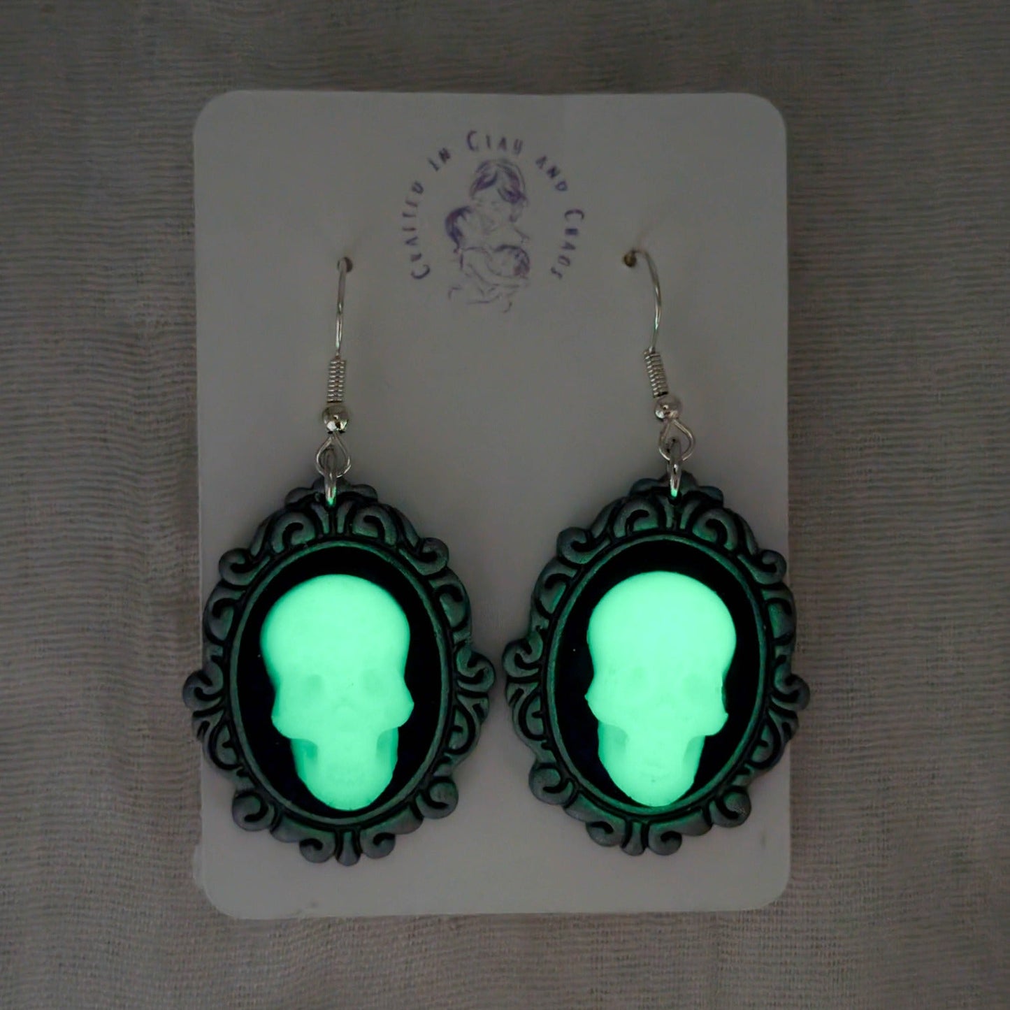 Glow demonstration showing vintage frame skull earrings shining green in the dark