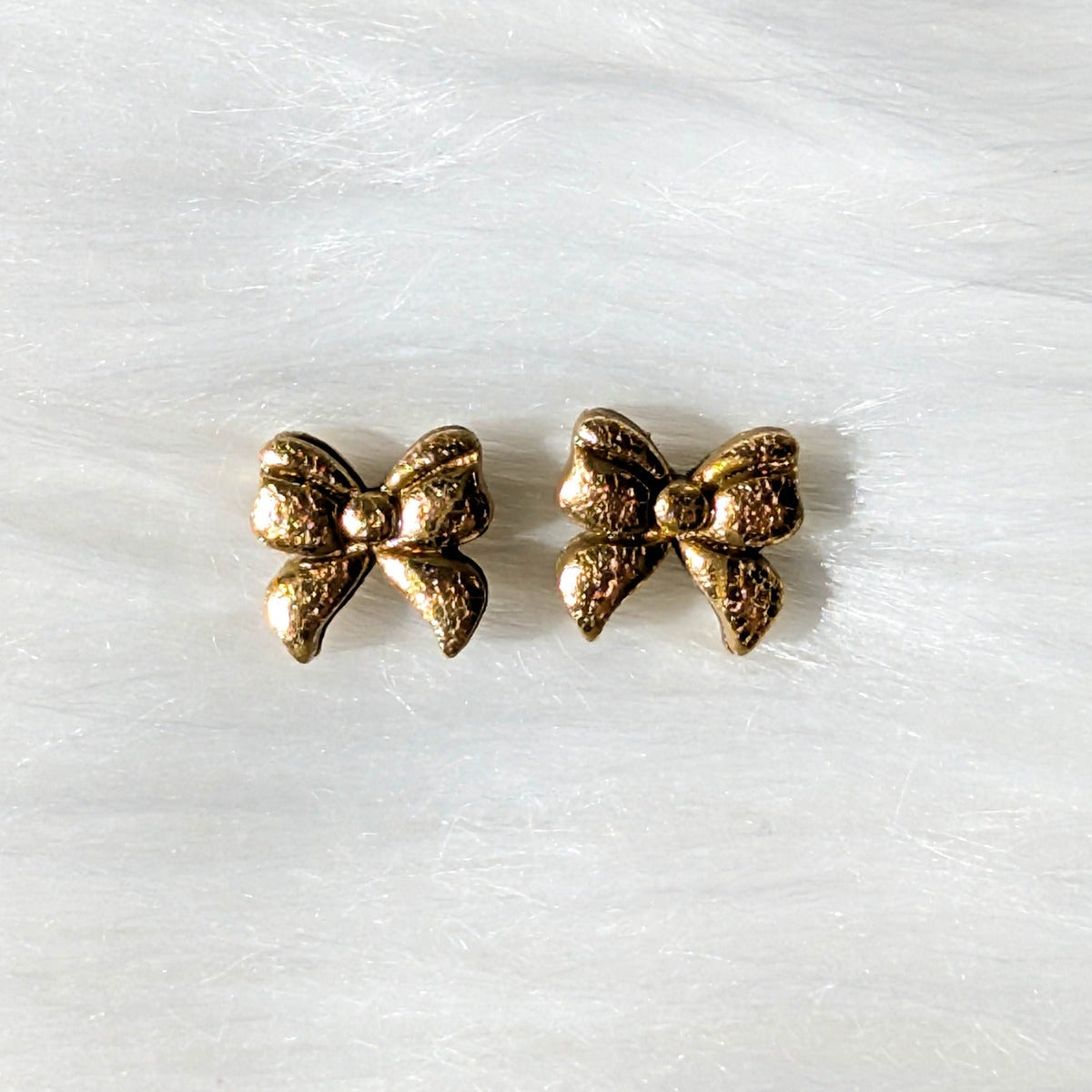 Gold foil crackle polymer clay bow stud earrings on a soft white background
