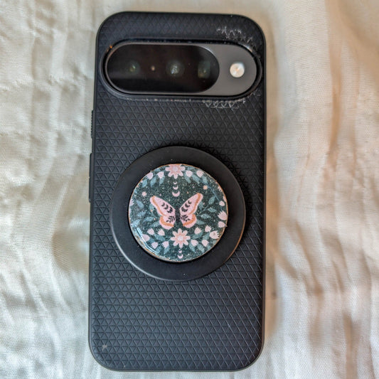 Witchy botanical moth MagSafe phone grip displayed on a black smartphone