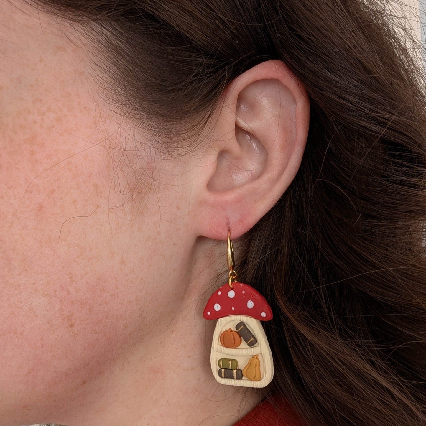 Cottagecore mushroom bookshelf earring with tiny books and pumpkins worn on ear