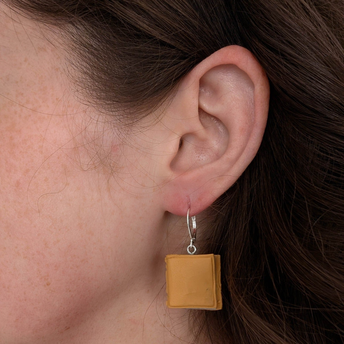Mustard yellow smooth miniature book earring worn on ear
