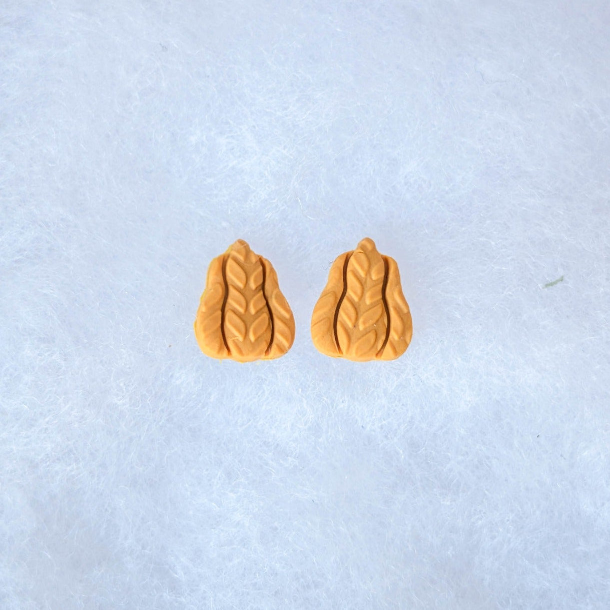 Tiny mustard yellow elongated gourd stud earrings with a raised knitted texture