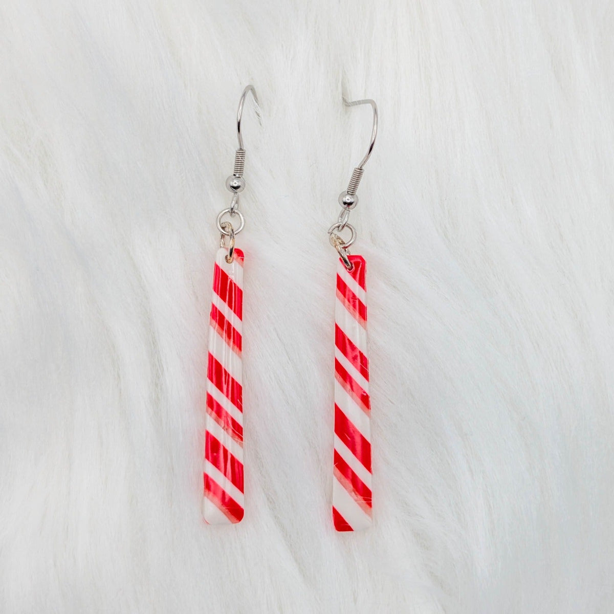 Long narrow bar dangle earrings in red, white, and translucent candy cane stripes.