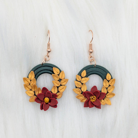 Close-up of handmade vintage Christmas wreath earrings with gold leaves, red poinsettias, and gold-plated stainless steel hooks.