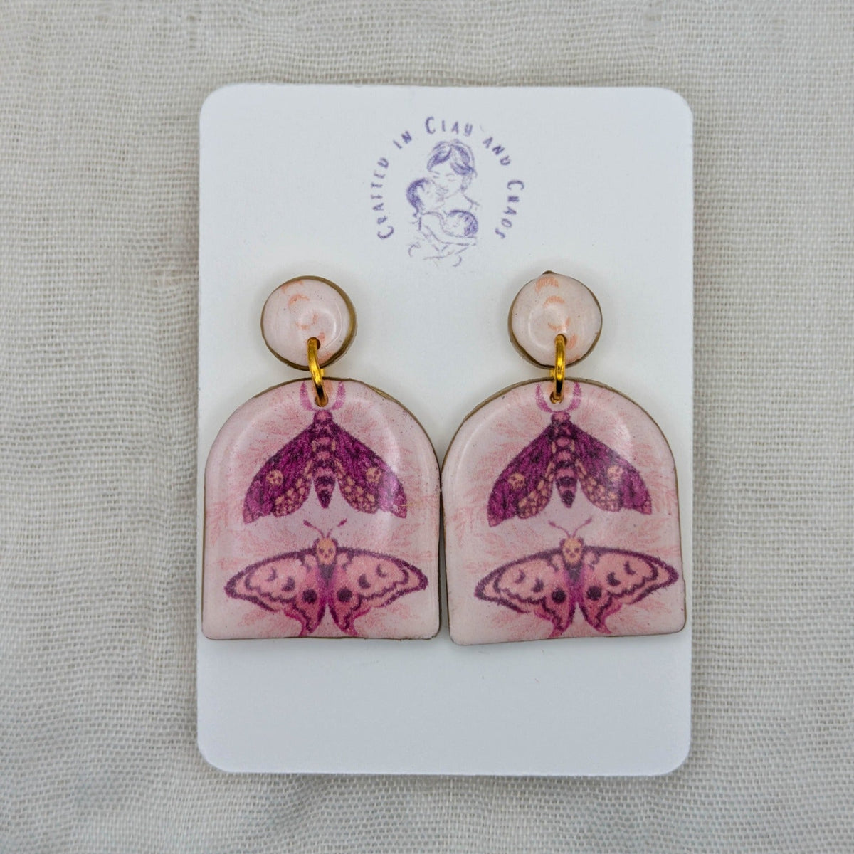 Pastel pink moth arch earrings with gold edging and celestial moth artwork