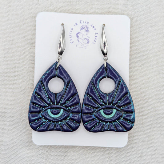 Purple galaxy shimmer planchette earrings with teal highlights, all-seeing eyes, and stainless steel hooks