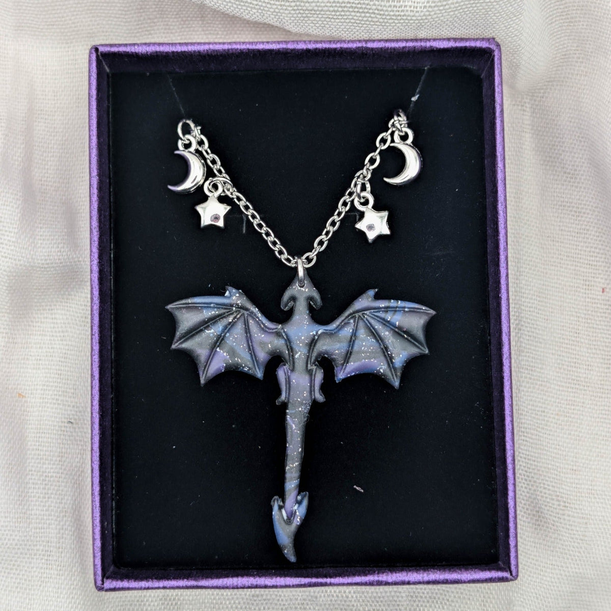 Silver-tone dragon necklace with marbled pendant and moon and star chain charms