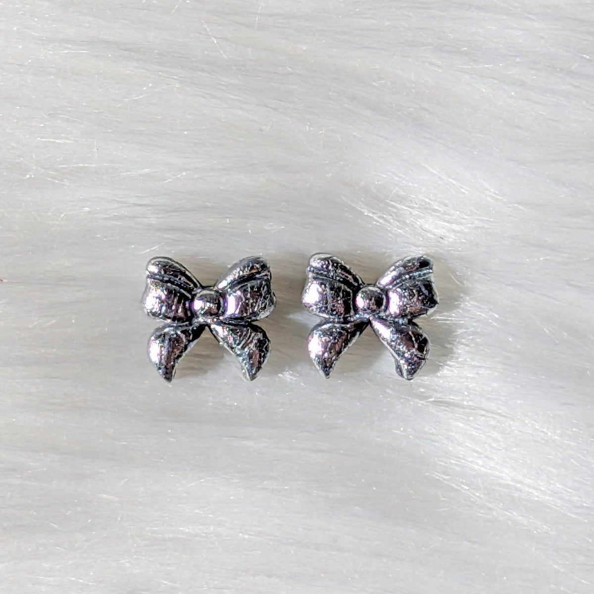 Silver foil crackle polymer clay bow stud earrings on a soft white background