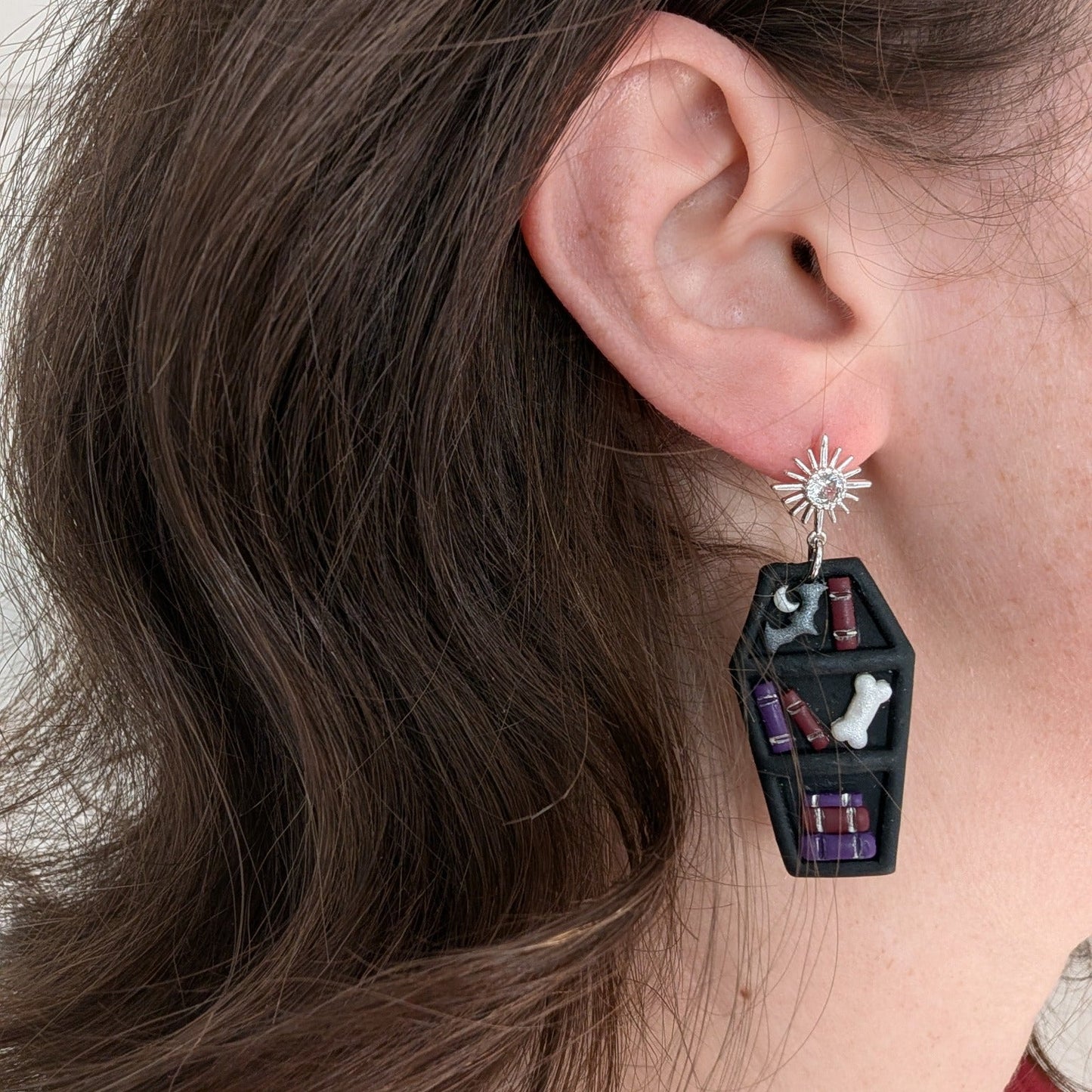 Vampire coffin bookcase earring with tiny books, bat, moon, and bone worn on ear