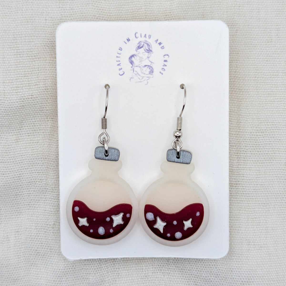 Wine red translucent potion bottle earrings with celestial details and surgical-grade stainless steel hooks