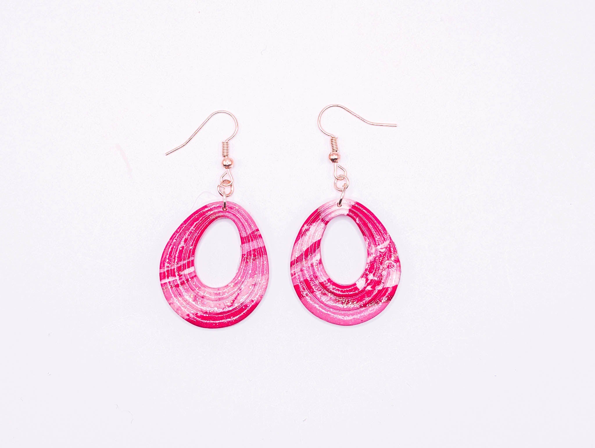 Pink marbled hoop earrings on a white background