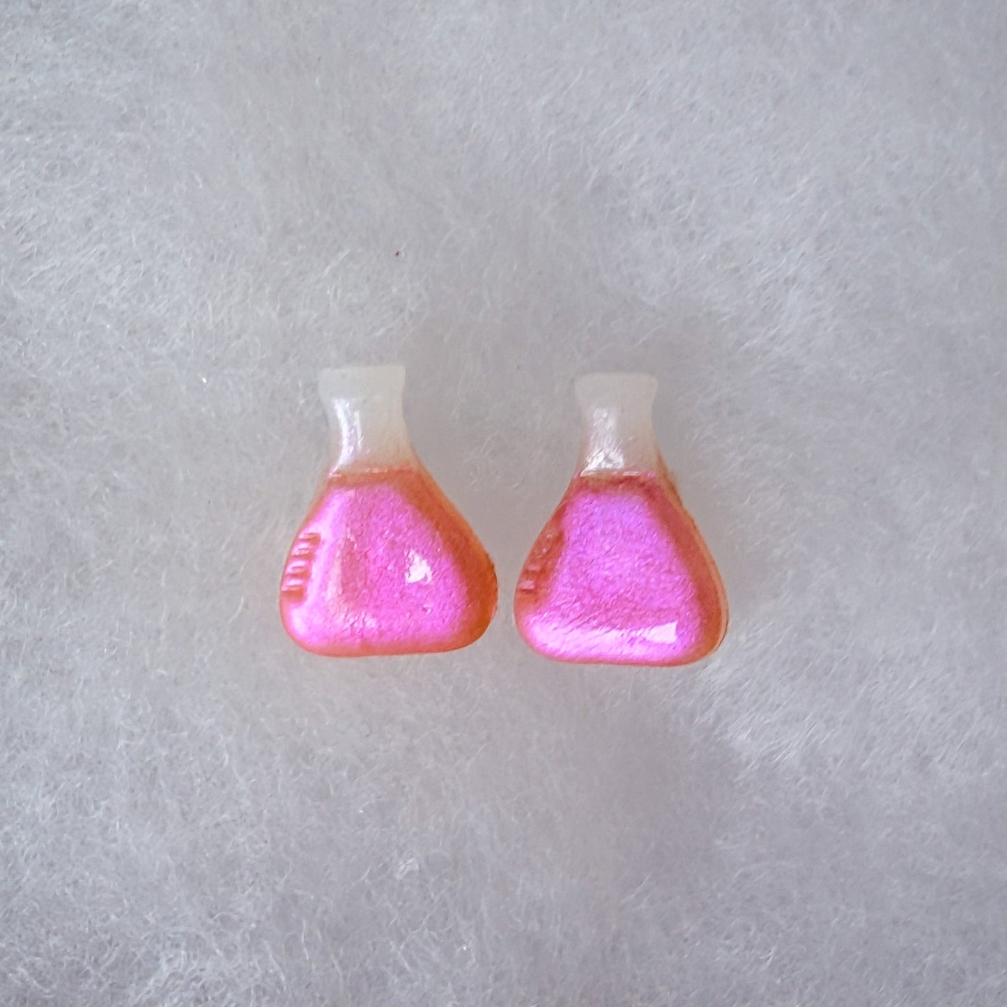 A pair of beaker shaped stud earrings with a translucent top and a glittery magenta to purple colorshift finish.