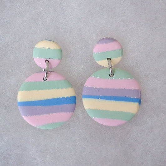 A pair of pastel striped dangle earrings with a small round top piece connected by a silver jump ring to a larger circular drop. The earrings feature horizontal stripes in pink, light blue, mint green, lavender, and cream.