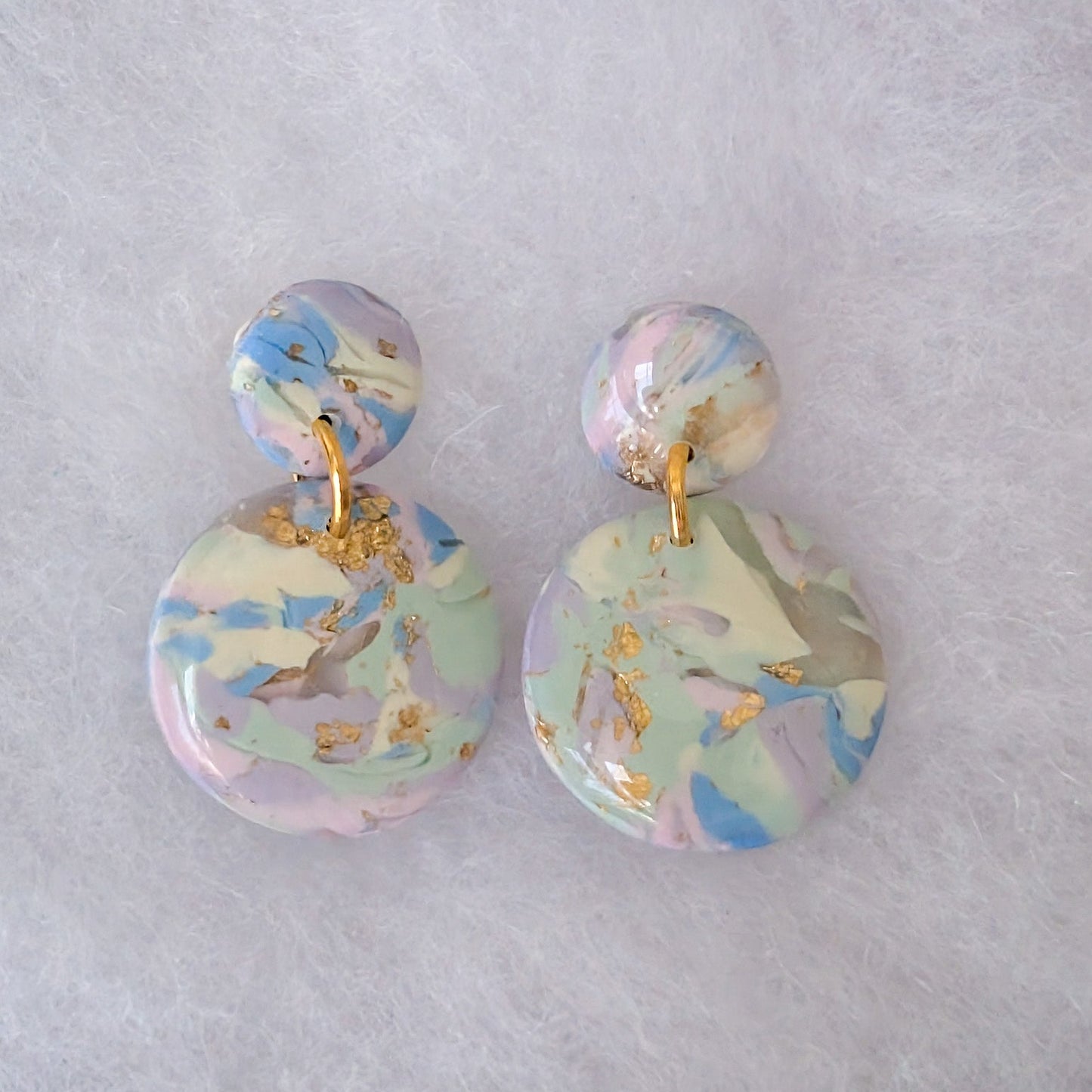 A pair of double-drop dangle earrings with a pastel marble pattern in pink, blue, and green, accented with gold foil flakes and gold-tone metal hardware.