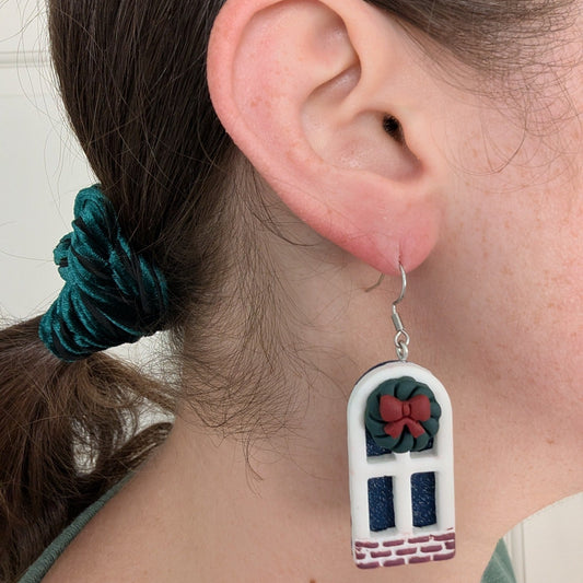 Christmas window earrings shown being worn, with wreath details and snowy blue panes.