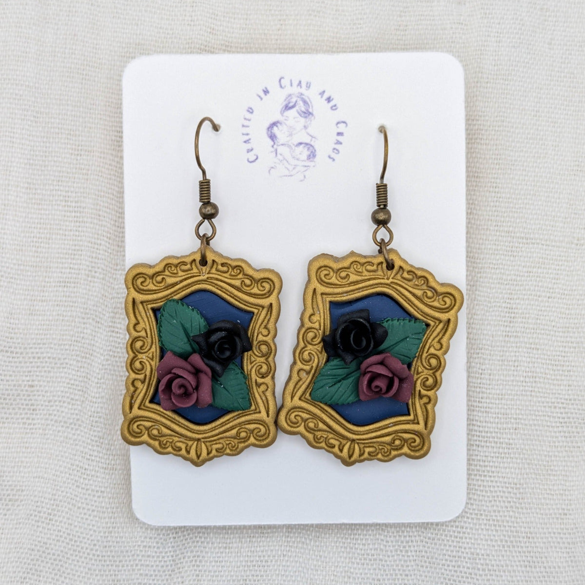 Antique gold vintage frame earrings with deep blue background, sculpted black and burgundy roses, and bronze-tone hooks