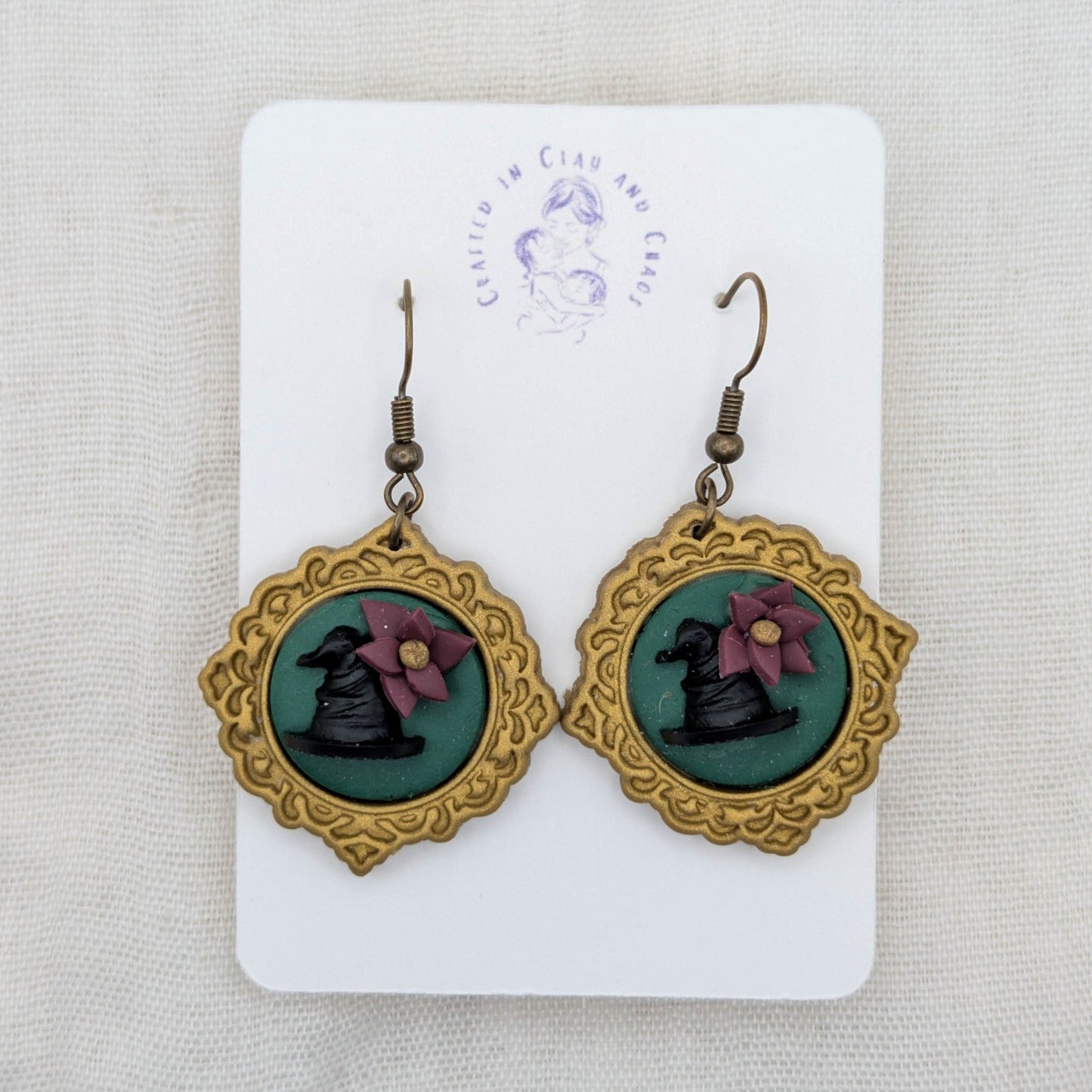 Antique gold round vintage frame earrings with green background, black witch hats, burgundy flowers, and bronze-tone hooks