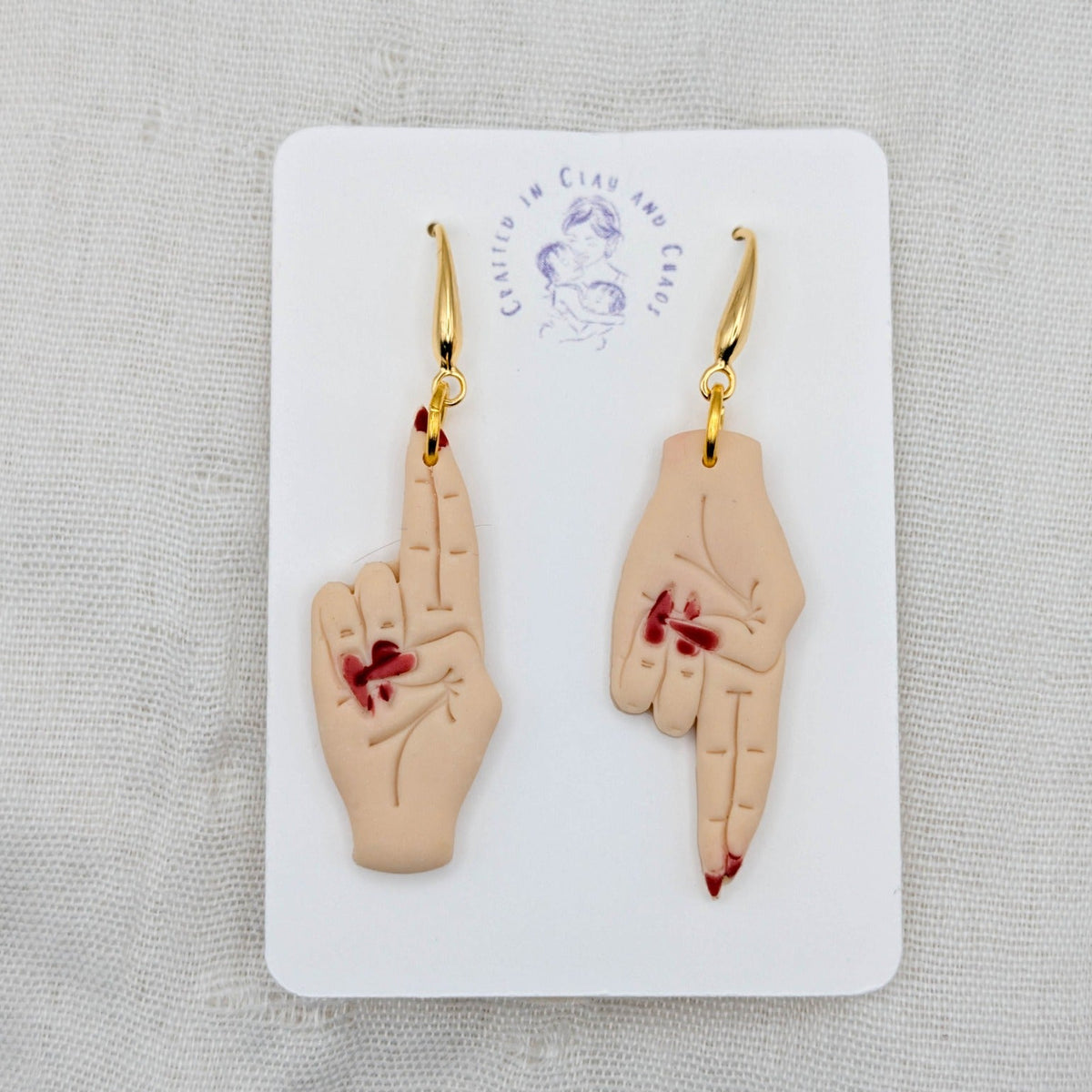 As Above, So Below light beige hand earrings with deep red painted nails and 18K gold-plated hooks