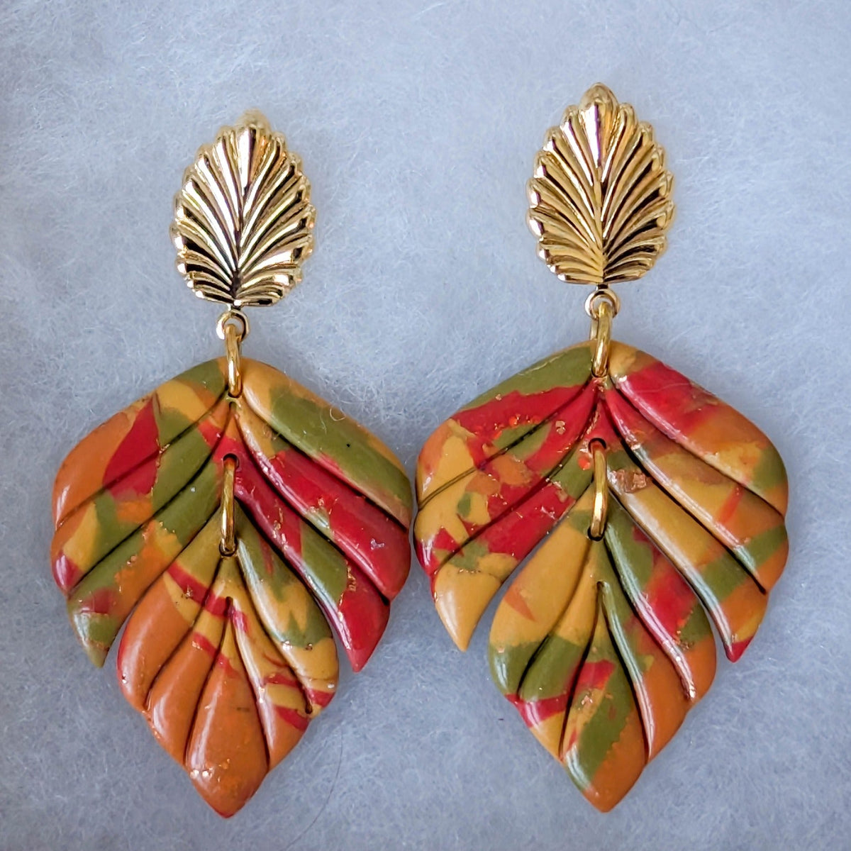 Close-up of colorful marbled polymer clay leaf earrings with 18K gold-plated brass leaf studs