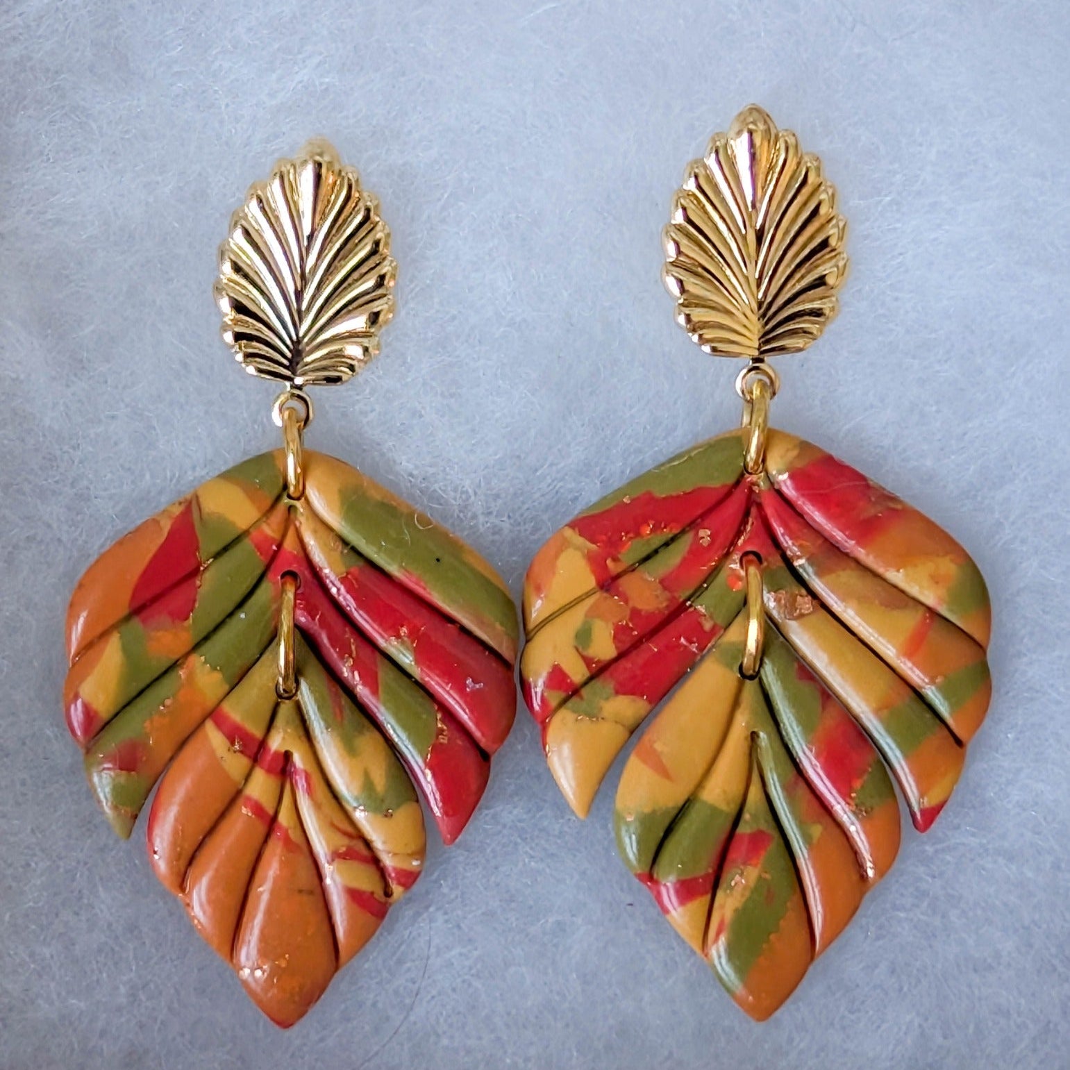 Close-up of colorful marbled polymer clay leaf earrings with 18K gold-plated brass leaf studs