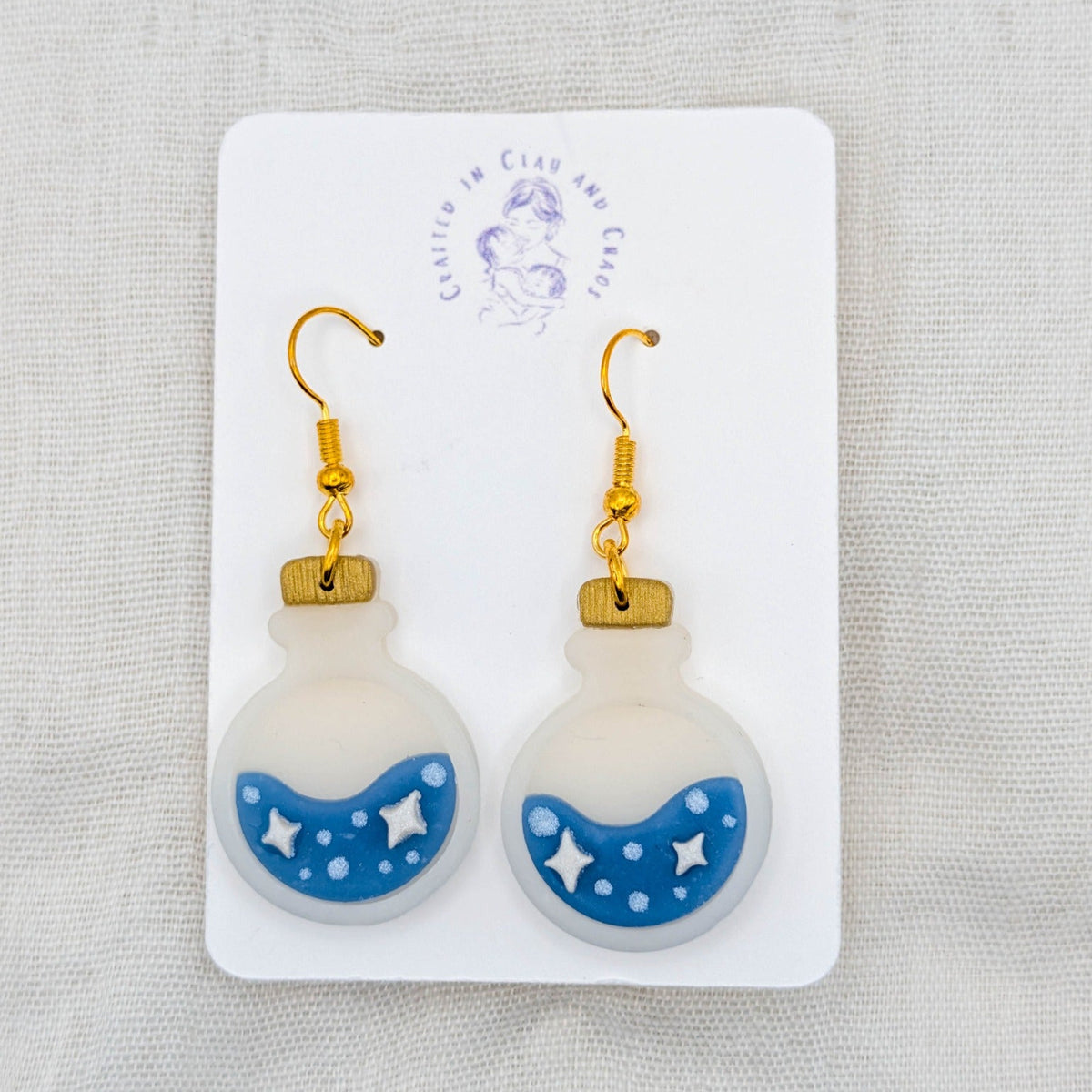 Blue translucent potion bottle earrings with white celestial details and 18K gold-plated stainless steel hooks