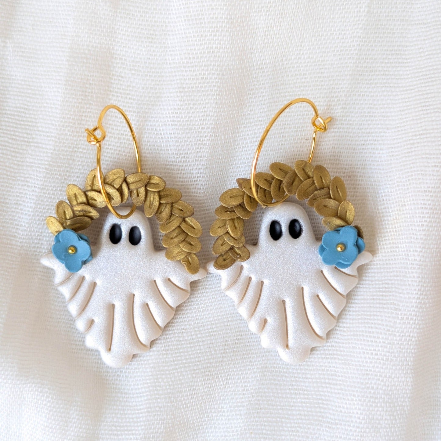 Pearlescent botanical ghost earrings with gold leaf crowns, blue flowers, and gold hoops