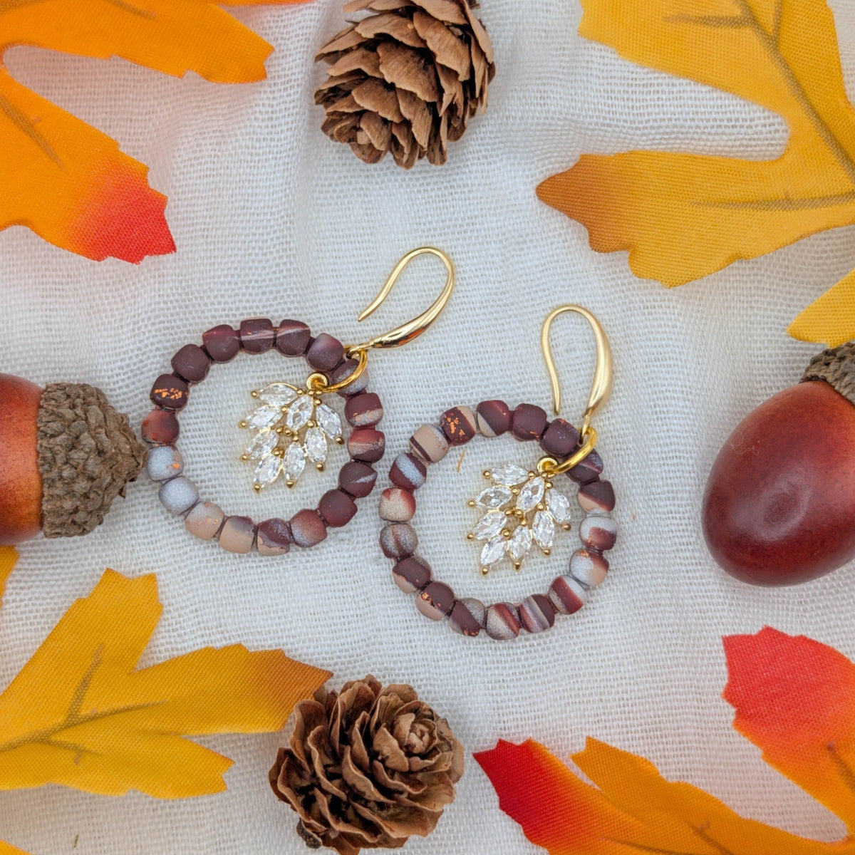 Brown marble wreath earrings with gold hooks and clear leaf cluster accents styled for autumn