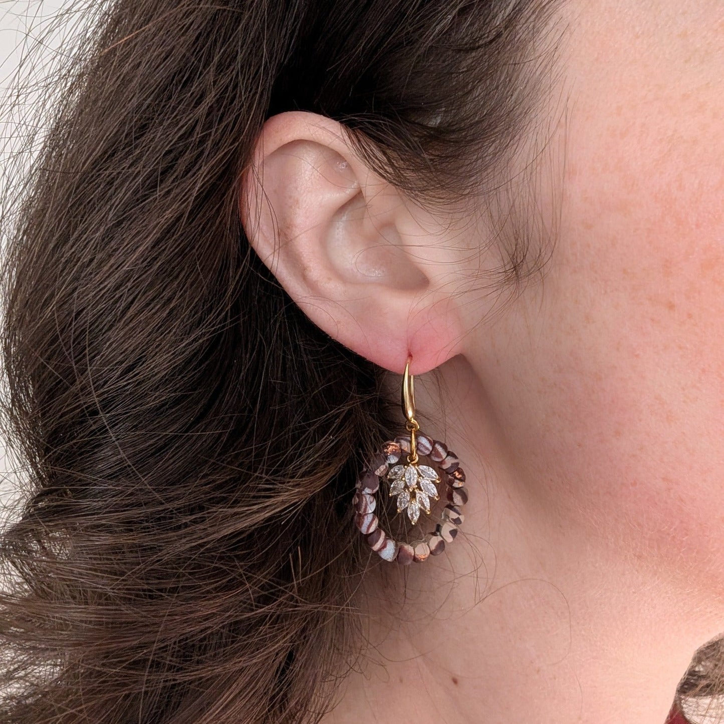 Brown marble wreath earring with gold leaf charm worn on ear