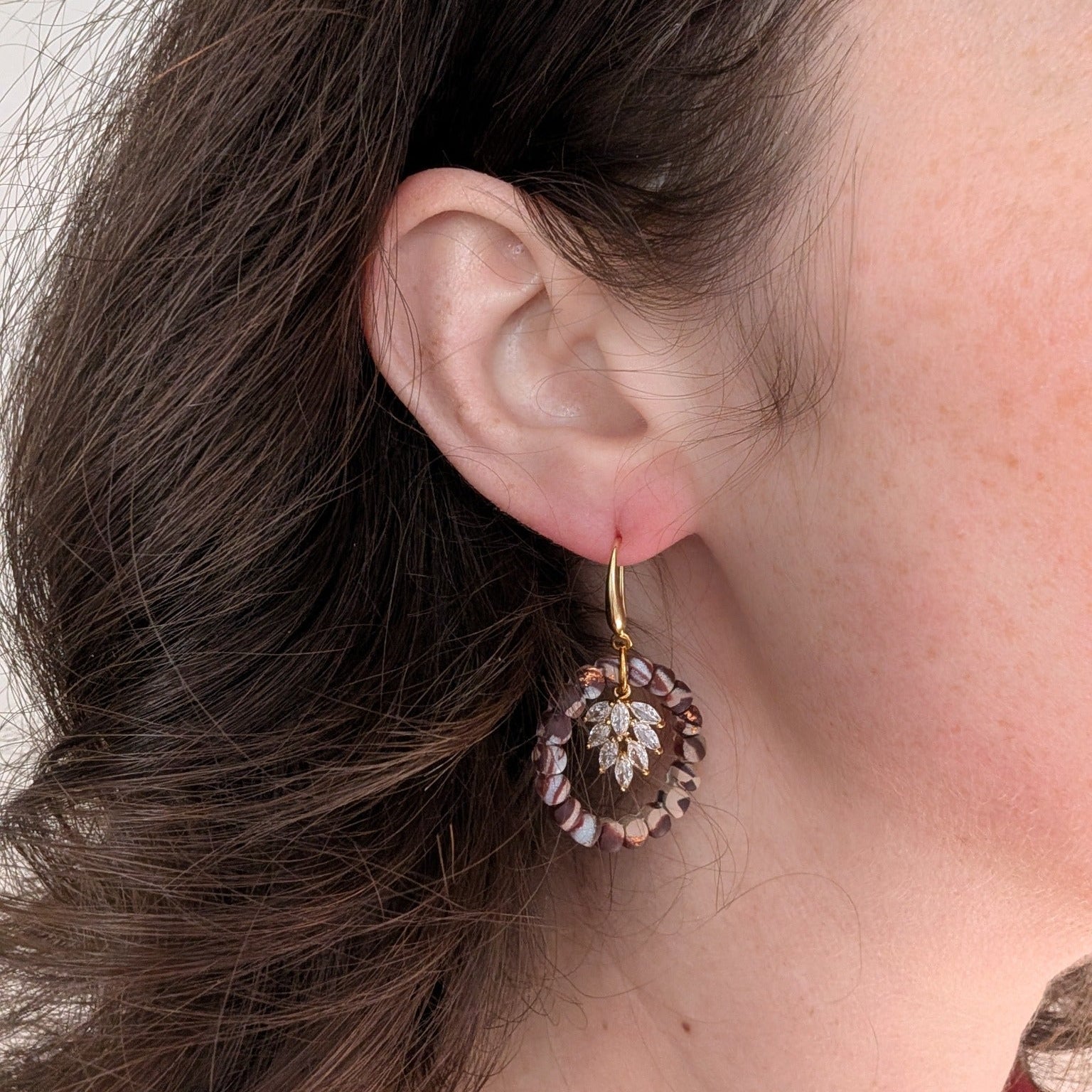 Brown marble wreath earring with gold leaf charm worn on ear