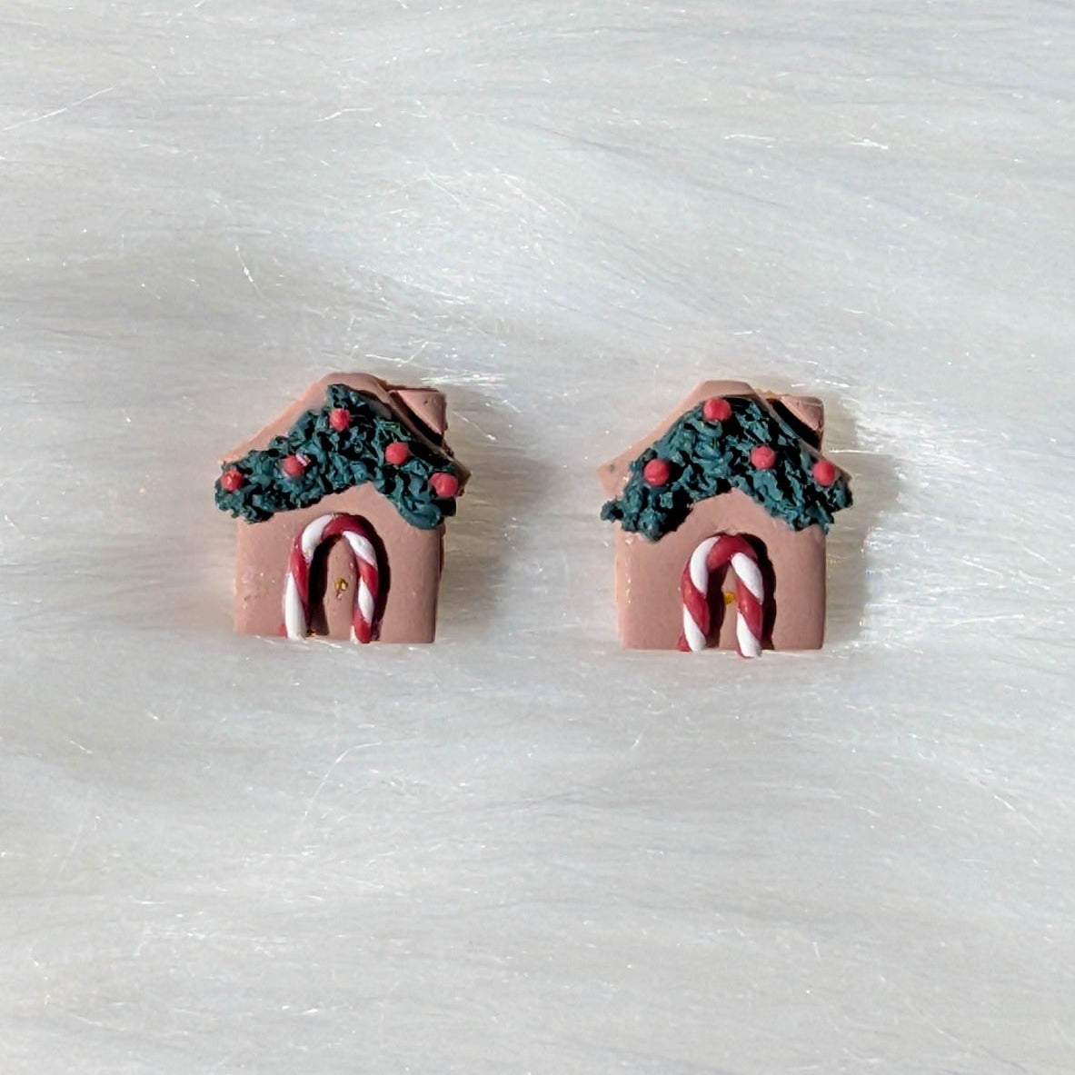 Close-up of gingerbread house studs with green garland, red berries, and candy cane doors