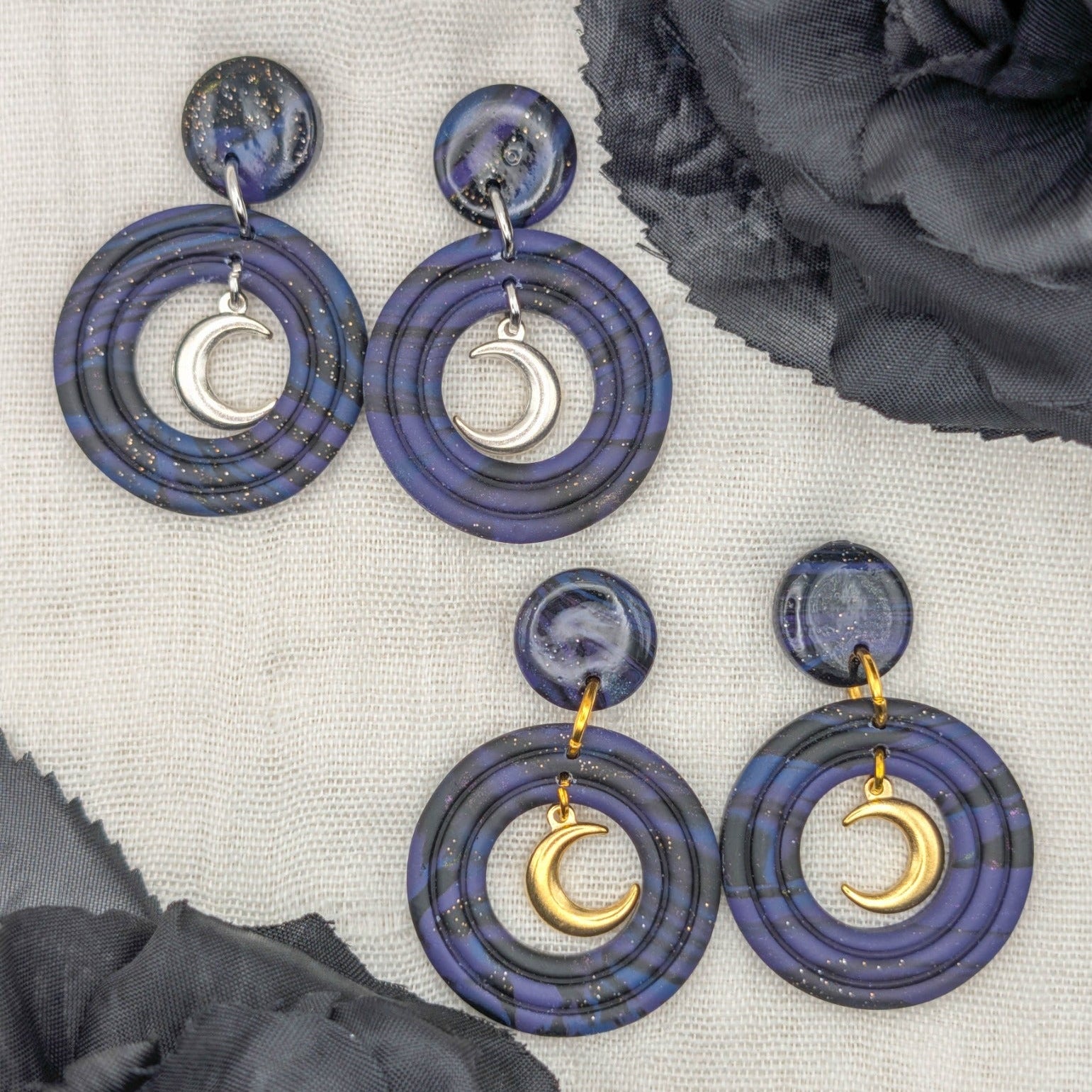 Gold and silver celestial marble crescent moon earrings styled with black flowers, showing both hardware finishes
