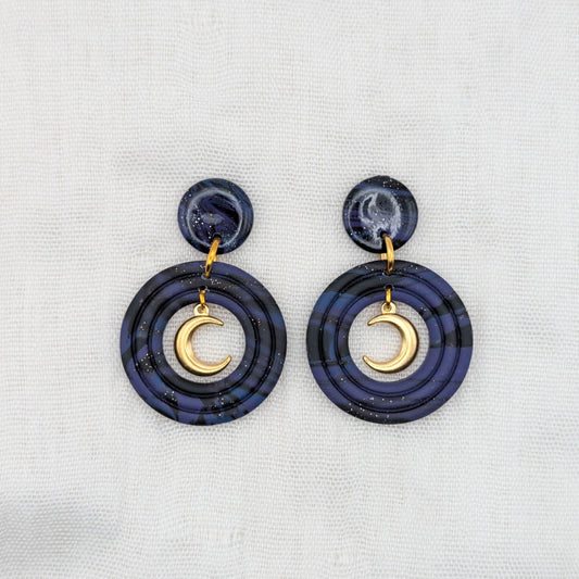 Gold-toned celestial crescent moon earrings with deep purple, midnight blue, and black marbled double-circle drops
