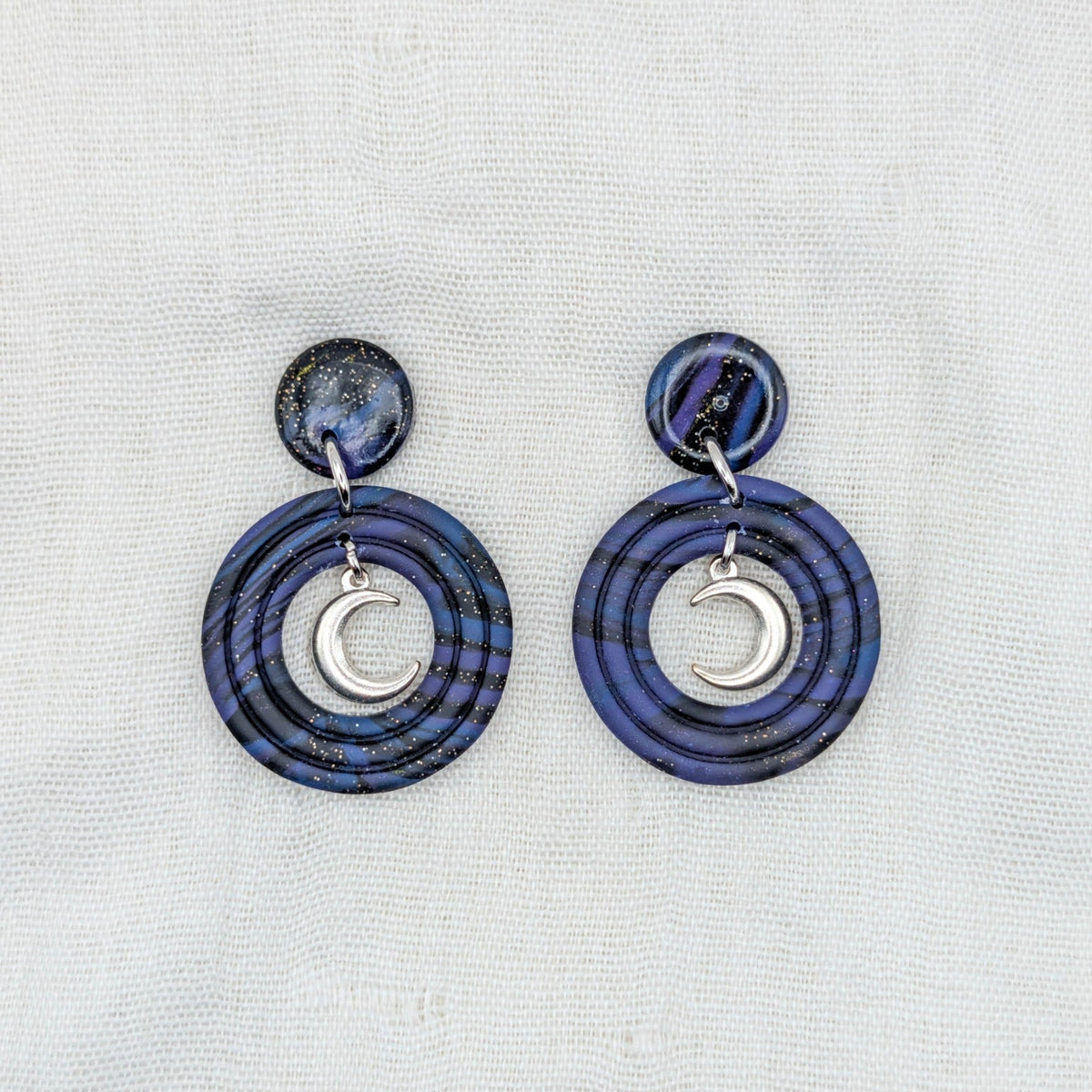 Silver-toned celestial crescent moon earrings with deep purple, midnight blue, and black marbled double-circle drops