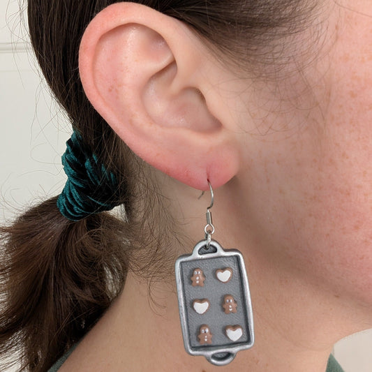 Christmas cookie baking sheet dangle earring shown on ear for scale