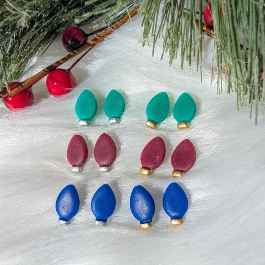 Six Christmas light stud earring variations styled with evergreen branches and red berries