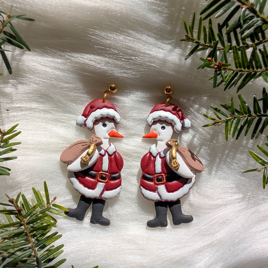 Pair of whimsical Santa Goose earrings styled with evergreen branches