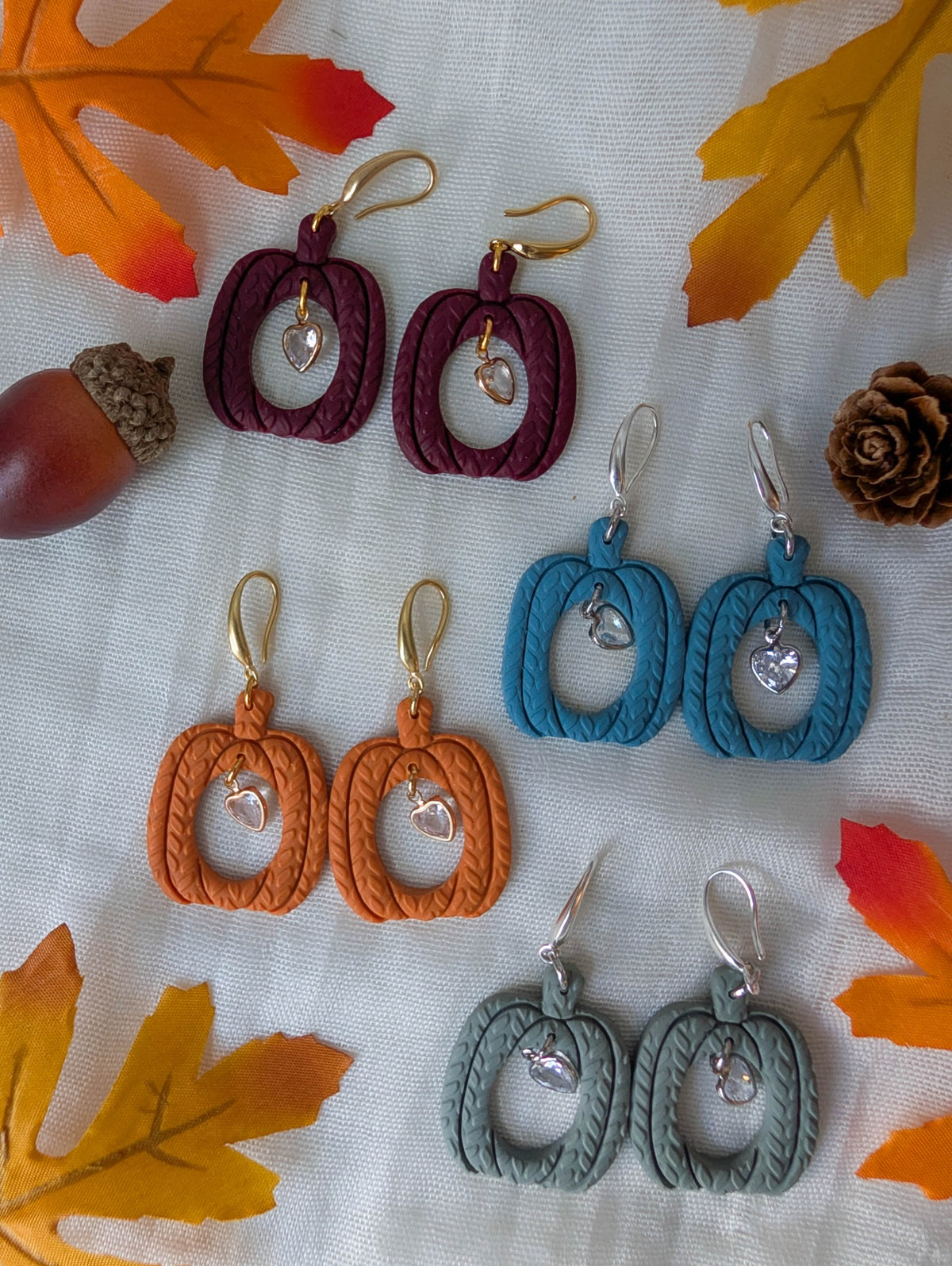 Knitted hollow pumpkin earrings in Crimson, Vintage Blue, Burnt Orange, and Sage Green with gold and silver heart charms