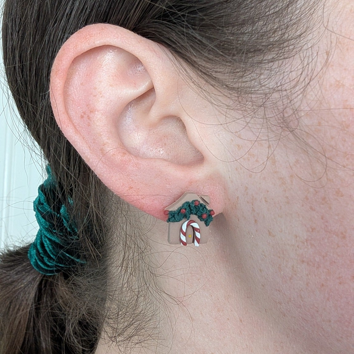 Decorated gingerbread house statement stud earring shown on ear for scale
