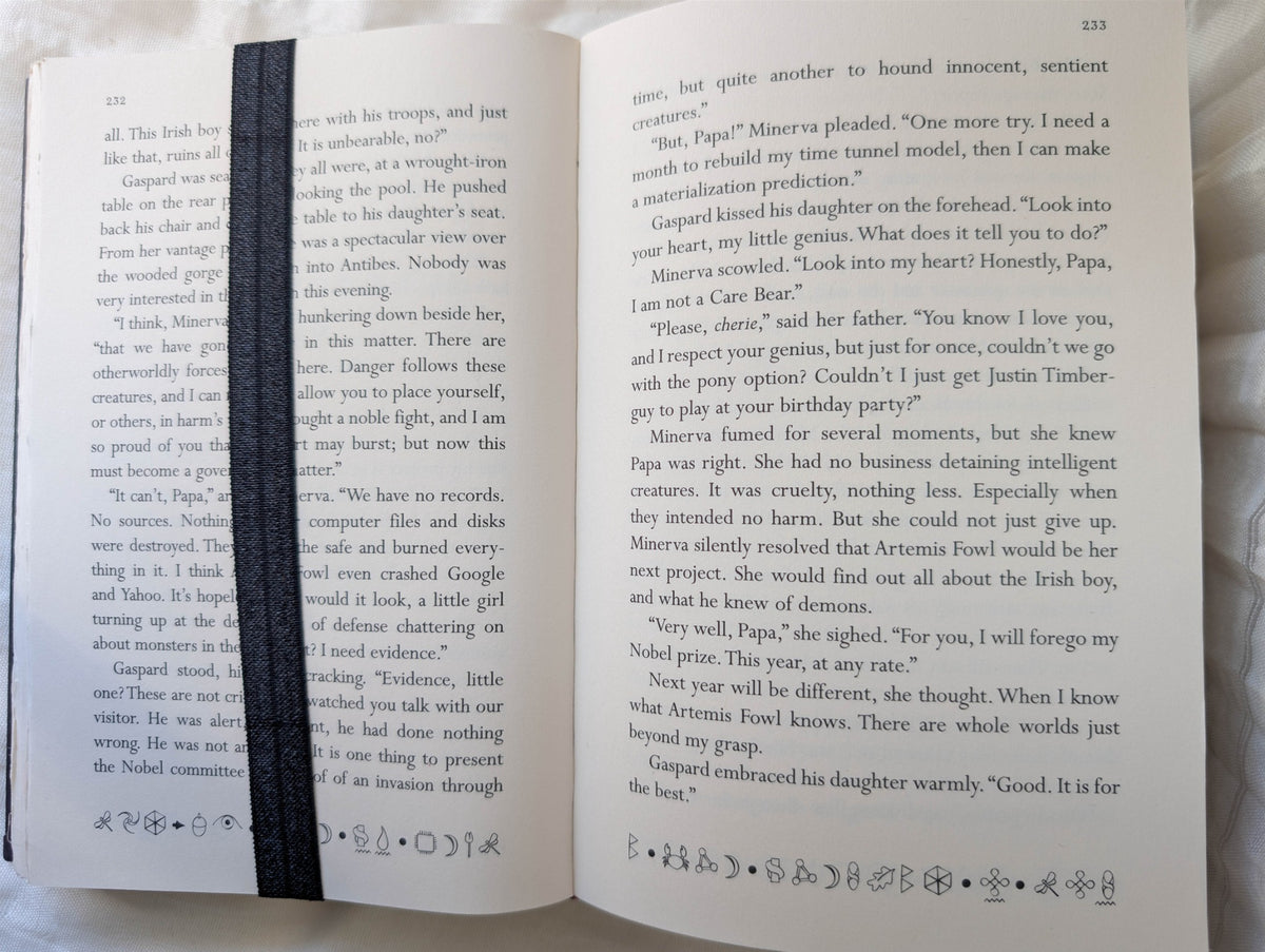 Black elastic wrap-around bookmark secured around the pages and cover of an open book