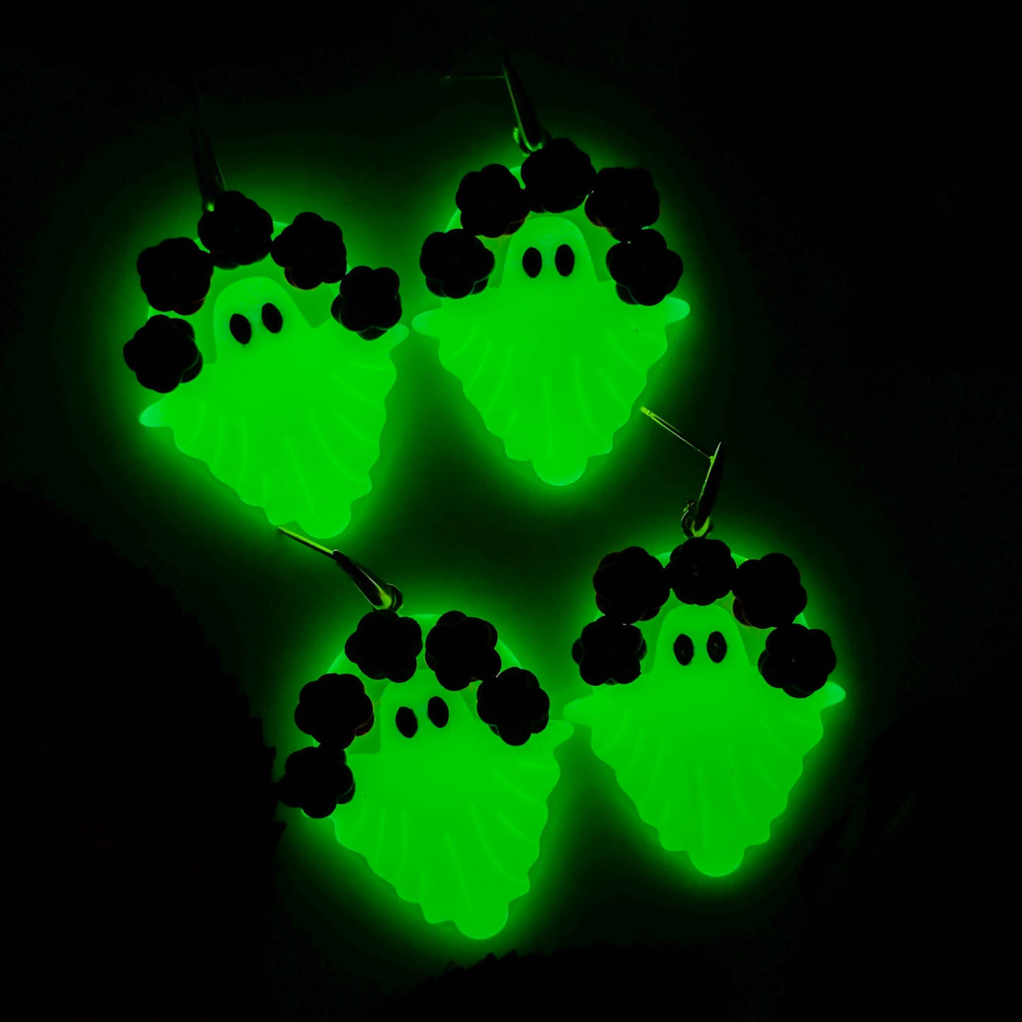 Glow-in-the-dark floral ghost earrings glowing bright green at night