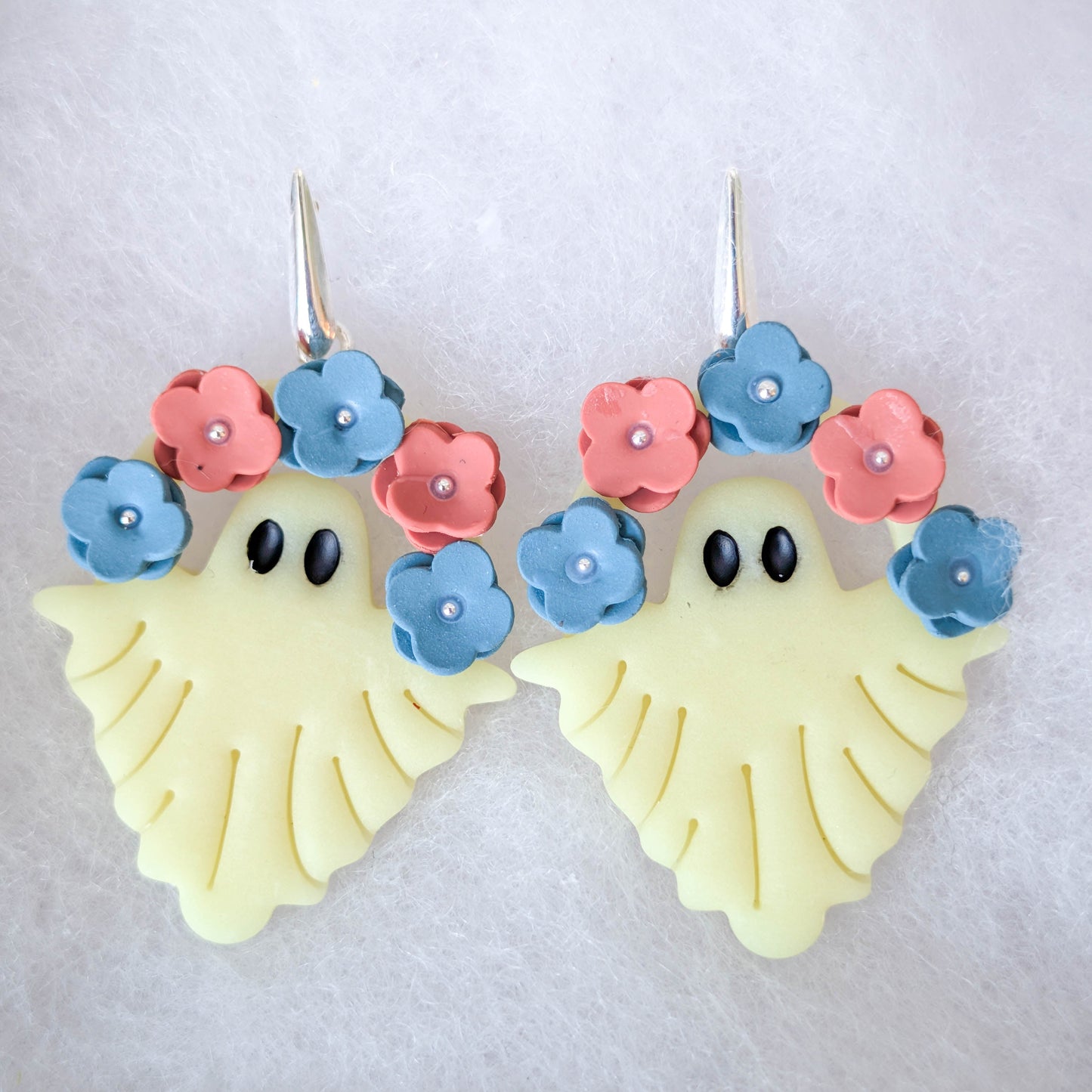Ivory glow-in-the-dark ghost earrings with blue and terracotta flower crowns and silver hooks
