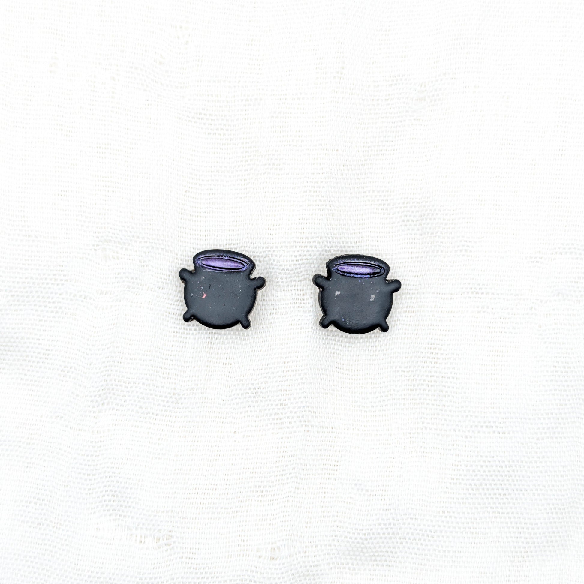 Black witch cauldron stud earrings with purple potion rims