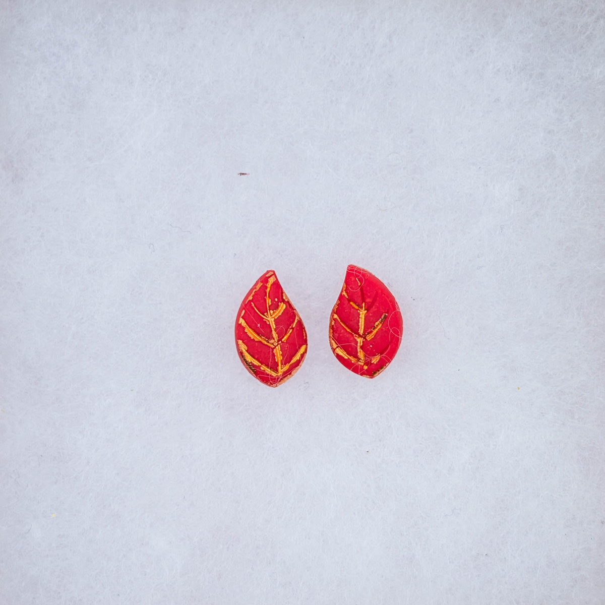Red autumn leaf stud earrings with bright gold-toned veining