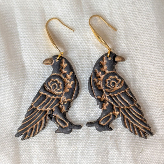 Black floral raven dangle earrings with gold floral and feather details and gold-tone hooks