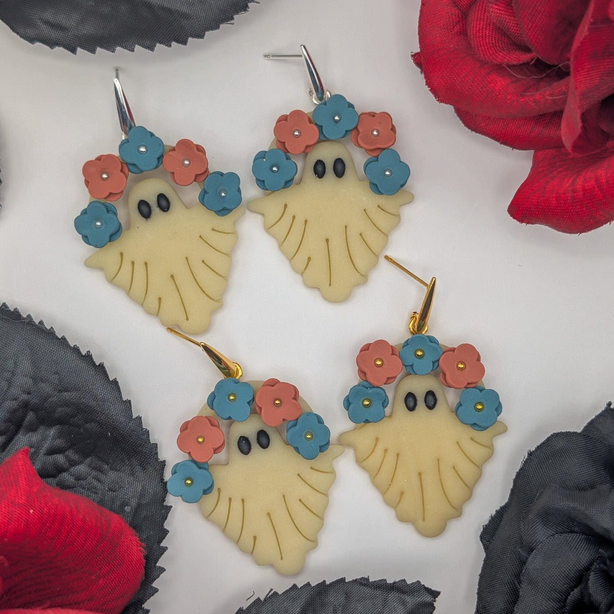 Handmade glow-in-the-dark ivory ghost earrings with teal blue and terracotta floral crowns in gold and silver