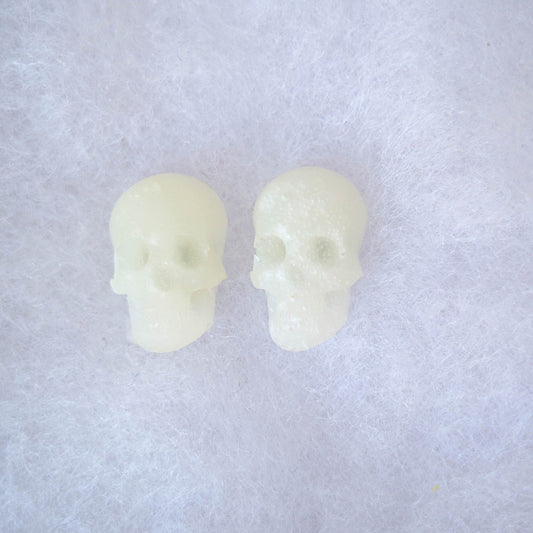 Translucent glow-in-the-dark skull stud earrings shown in daylight