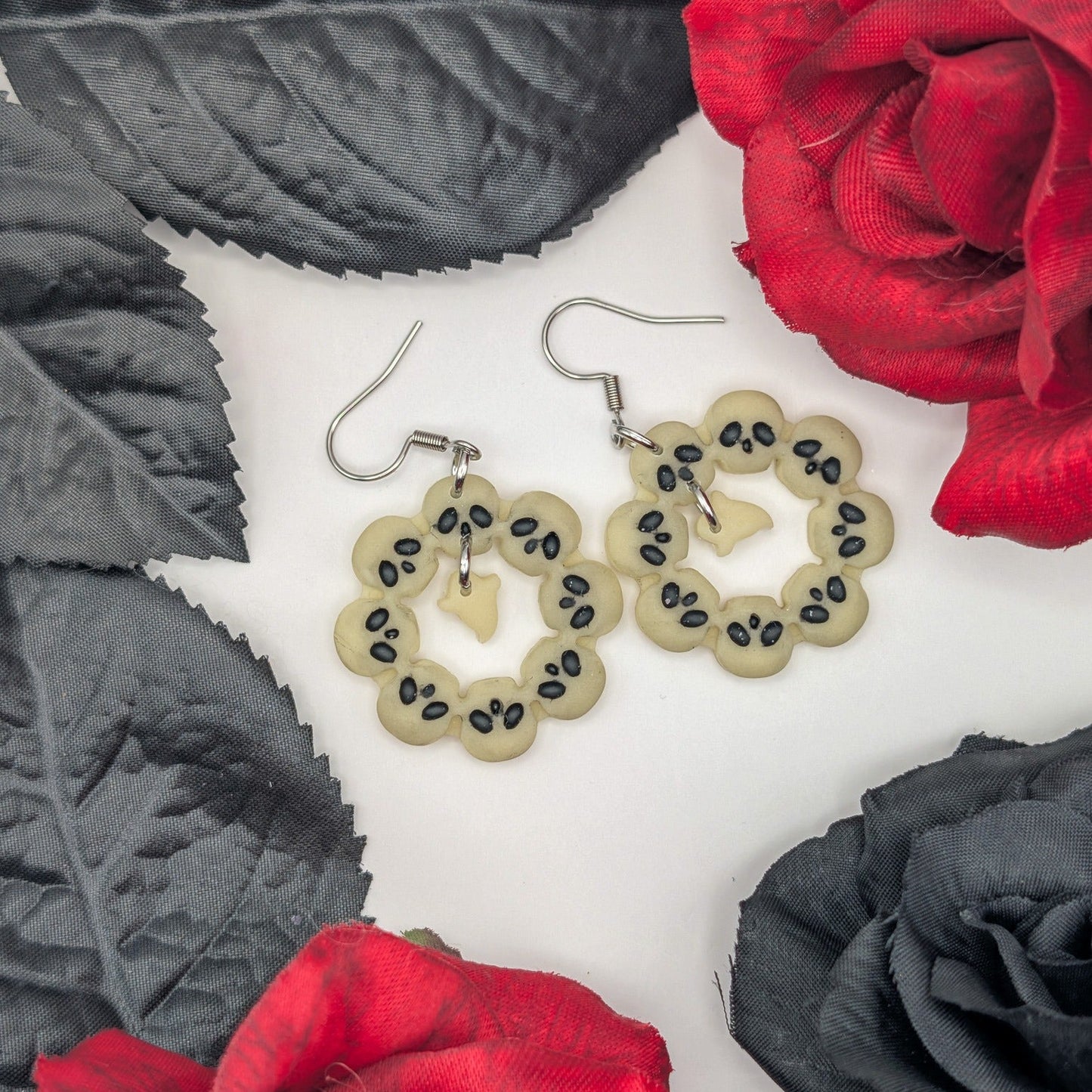Glow-in-the-dark skull wreath ghost earrings styled with red and black roses