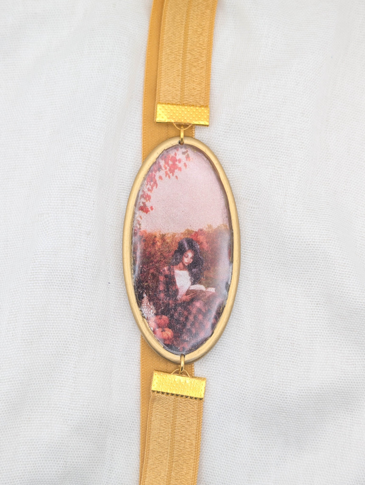 Gold framed fall polymer clay wrap-around bookmark showing a dark-haired reader among pumpkins and autumn leaves