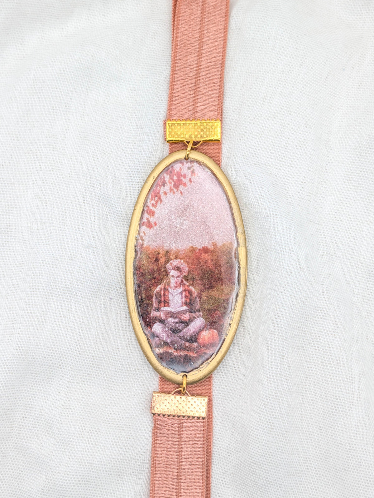 Gold framed fall polymer clay wrap-around bookmark showing a reader with a pumpkin and blush elastic band