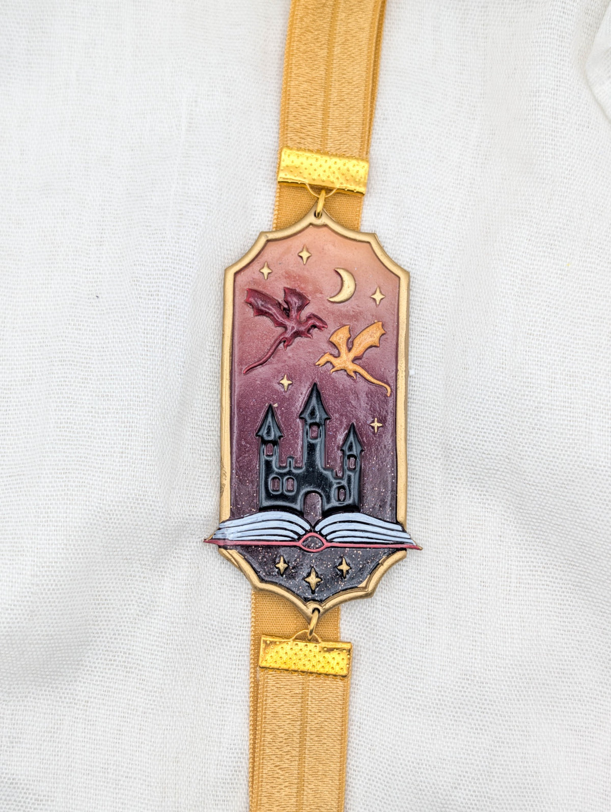 Gold framed fantasy polymer clay wrap-around bookmark with dragons, castle, crescent moon, and rose pink background